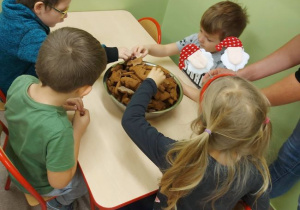 Na zdjęciu przedstawiono dzieci z grupy 4, które częstują się gotowymi ciasteczkami